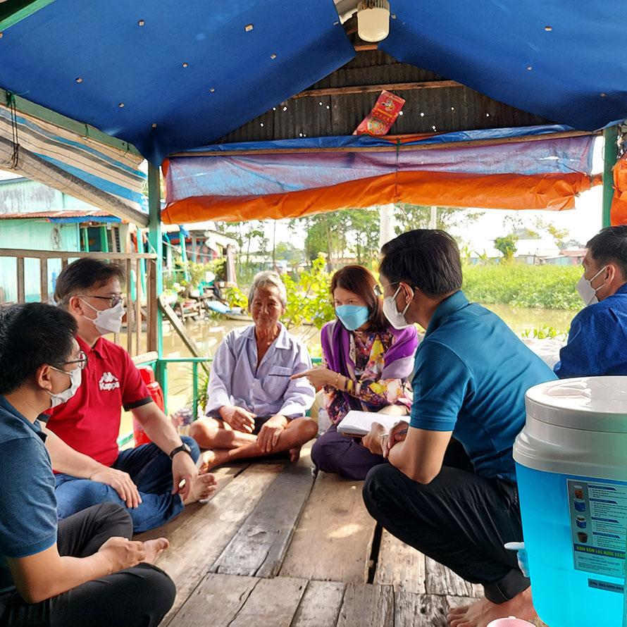 a small group sat on the porch of a house on the mekong river alongside a ISO-certified purifier