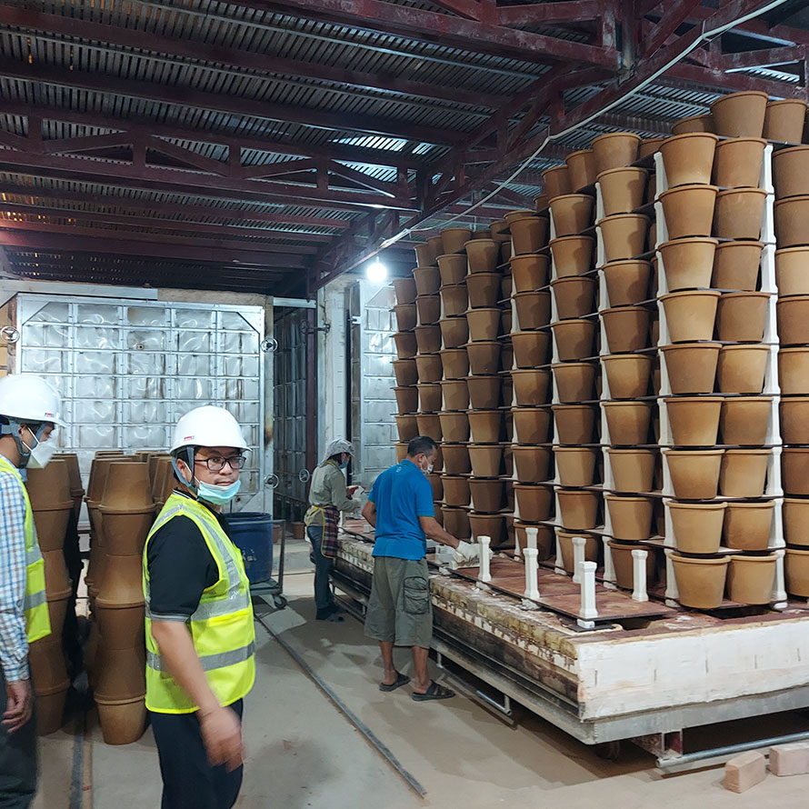 a warehouse with people in hard hats and rows of  ceramic pots